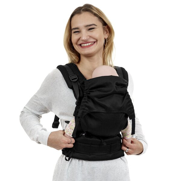 Mulher sorridente usando um Mei Tai Fidella Flowclick Toddler Chevron preto, com um bebé à frente.