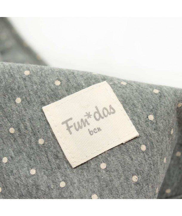 Vista de perto da manta, mostrando a dupla face: um lado com padrão de bolinhas e o outro lado em algodão liso.