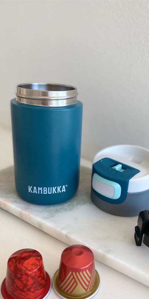 Garrafa térmica Kambukka Etna de 500ml, cor azul-petróleo, em primeiro plano, com a tampa 3 em 1 visível.