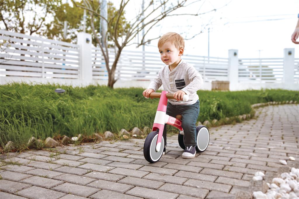 Menino a andar na bicicleta de equilíbrio Hape A minha primeira Vespa Rosa ao ar livre, aprendendo a equilibrar-se e a divertir-se.