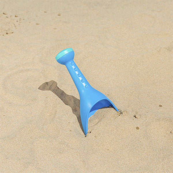 Hape pá regador de praia azul espetada na areia da praia num dia de sol.