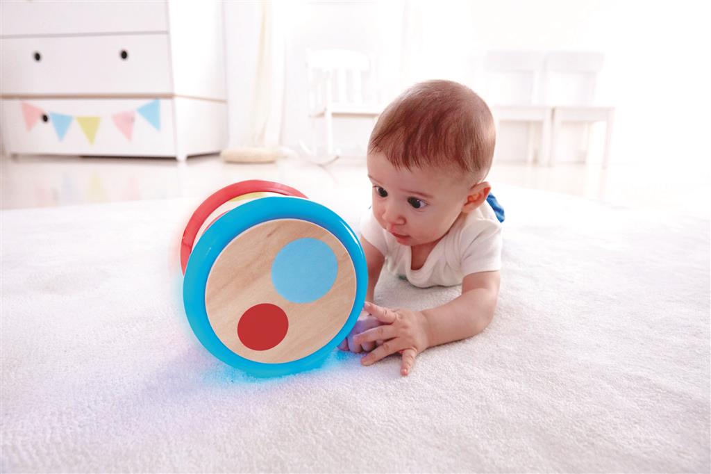 Bebé a brincar com o tambor Hape, explorando os sons e ritmos num ambiente seguro e estimulante.