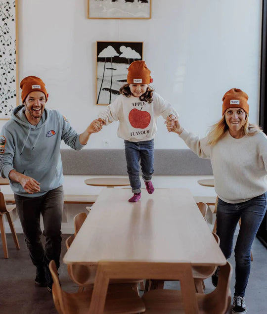 Mãe e filho a rir, ambos com gorro cinzento Hello Hossy. Mostra gorro criança em uso e etiqueta.