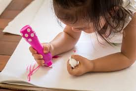 Close-up de criança a usar um marcador rosa Djeco de ponta de esponja para desenhar num papel branco.