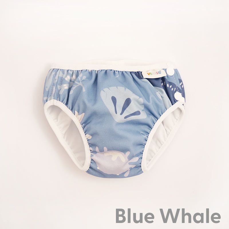 Cueca fralda de banho reutilizável ImseVimse com padrão de baleias azuis sobre fundo azul claro.
