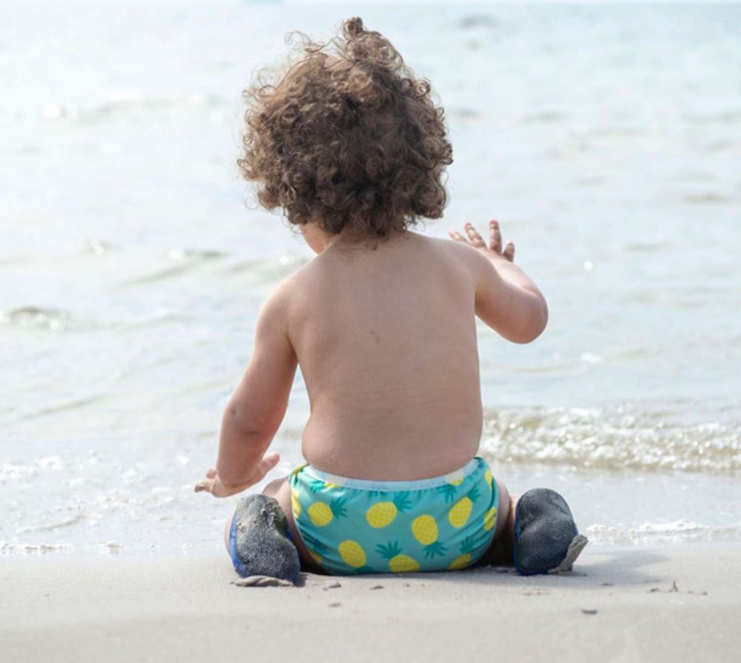 Bebé a brincar na areia da praia com fralda-cueca reutilizável de banho ImseVimse.