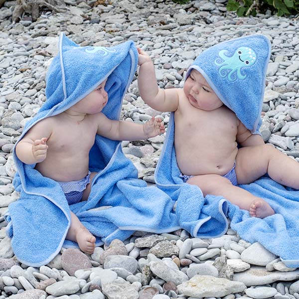 Dois bebés na praia protegidos com toalhas e fraldas de banho reutilizáveis ImseVimse.