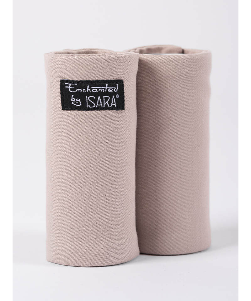 Par de protetores de alças Isara Teething Pads, cor cinza claro, fixados a uma alça de mochila de transporte de bebé, mostrando a função de proteção contra a saliva.