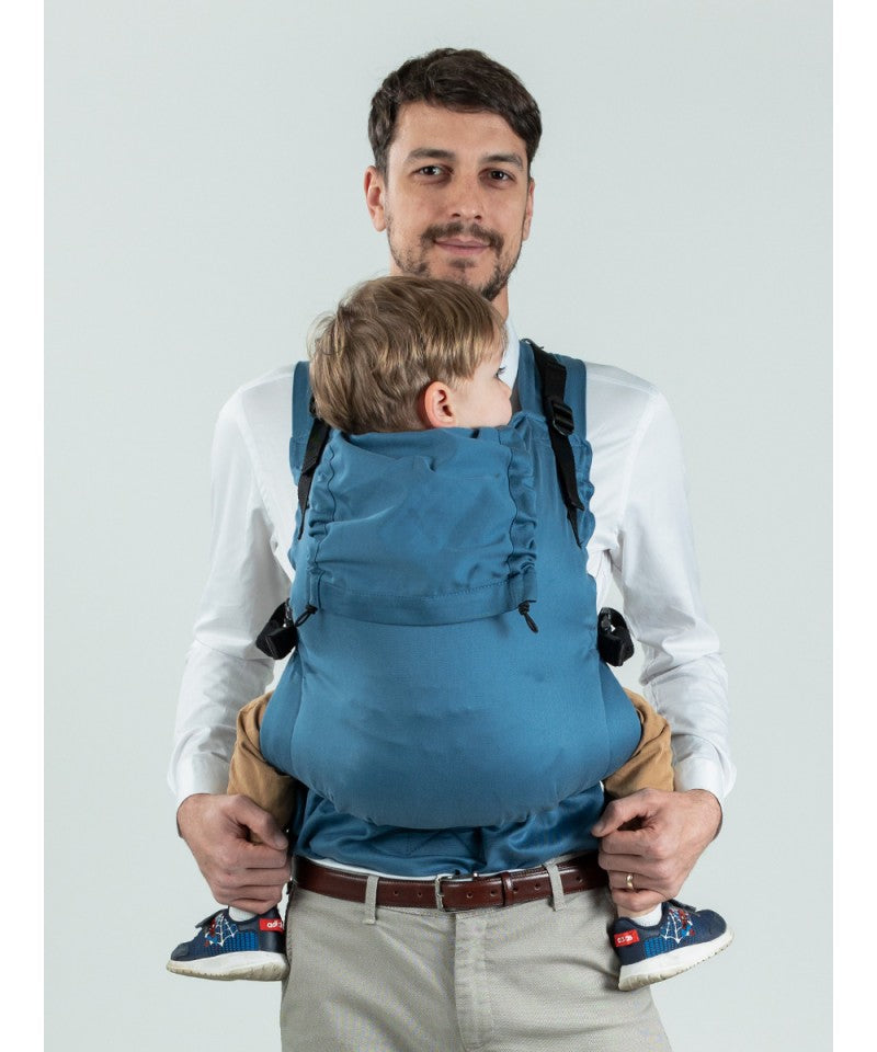 Homem usando a Mochila Isara Toddler Preschooler BLUESTONE, carregando um bebé.