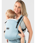 Imagem de uma mãe a usar a Mochila ISARA The ONE Ajustável AZZURRO com o bebé nas costas. A mãe está sorridente e o bebé parece confortável.