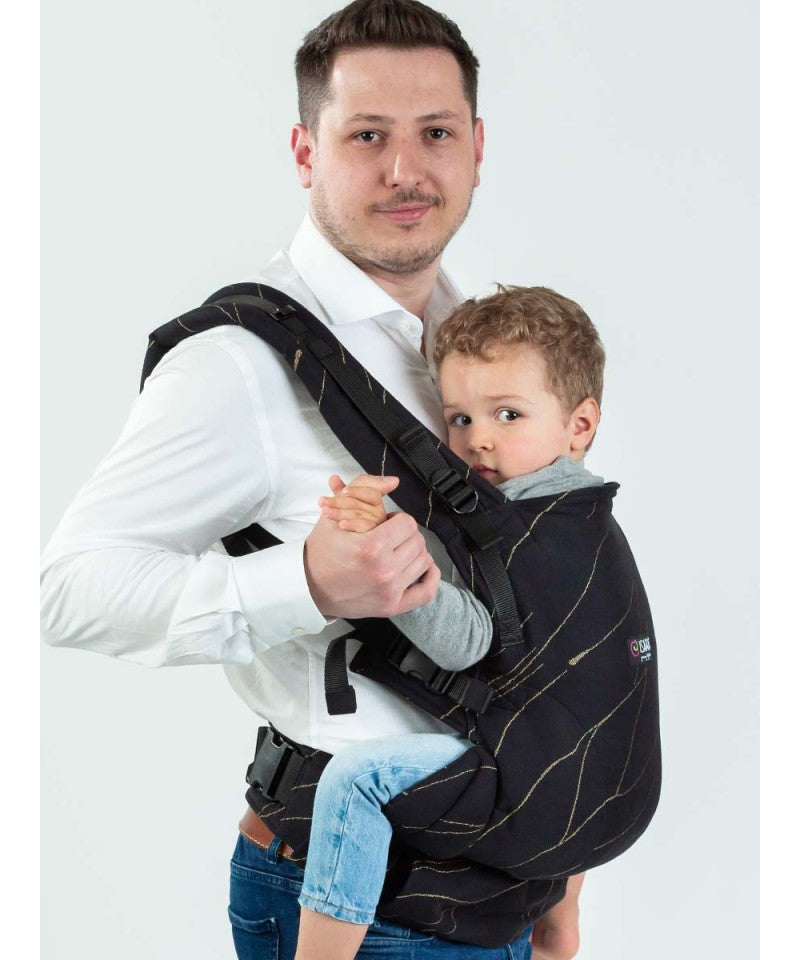 Homem de camisa branca a usar a Mochila Isara THE One Ajustável na cor Golden Nest, carregando uma criança pequena nas costas, destacando o ajuste versátil da mochila.