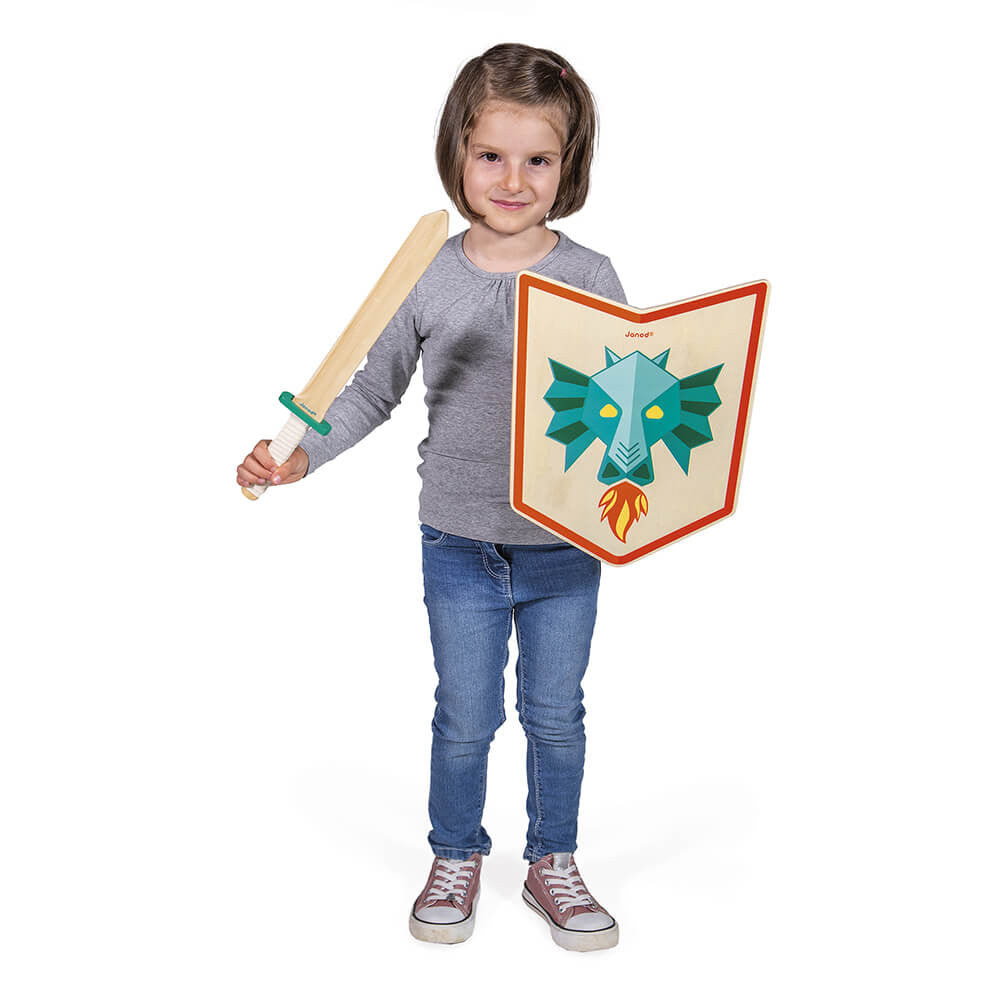 Menina a segurar o conjunto Janod de escudo e espada de madeira Dragão, sorridente e pronta para jogar.