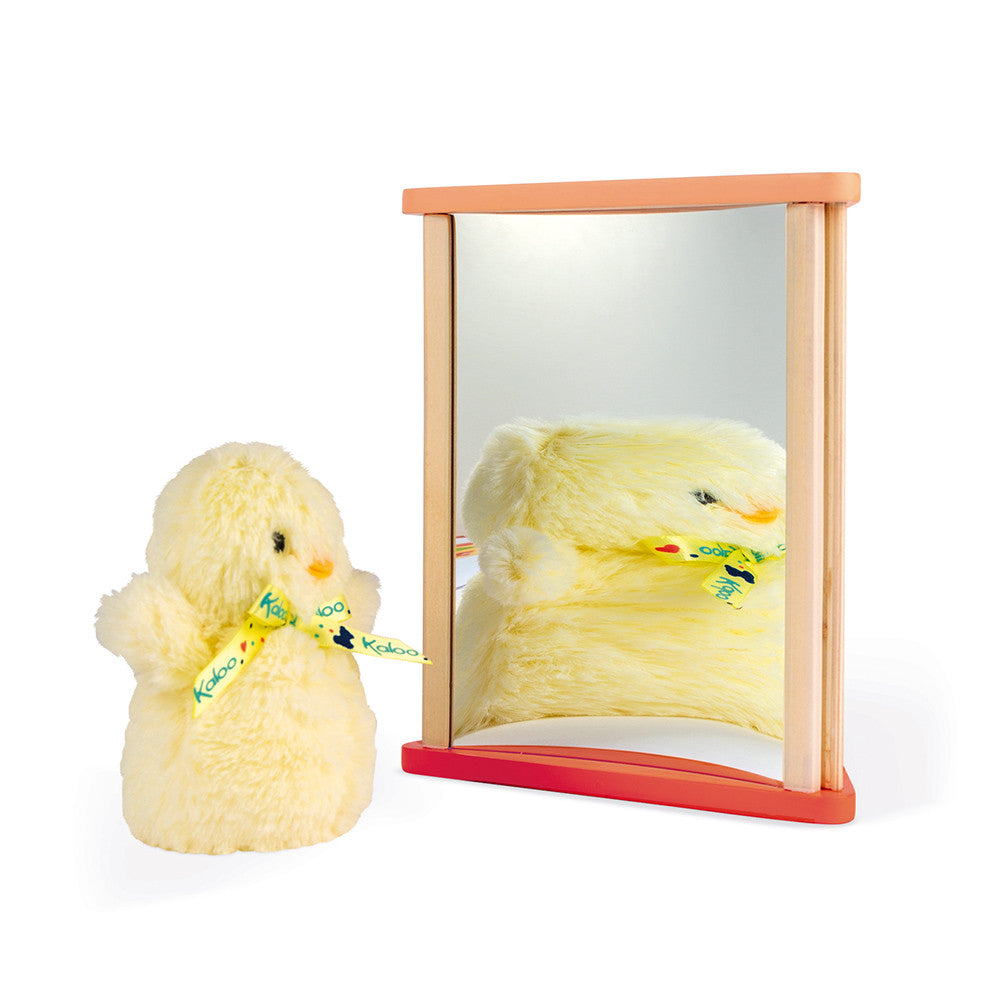 Um brinquedo de pintainho a olhar o seu reflexo no espelho da caixa Janod Essentiel.
