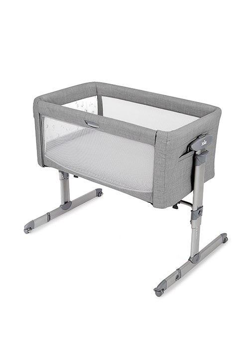 Berço Joie Roomie glide em cor neutra, montado e pronto a usar, com lateral abatida para co-sleeping junto a uma cama de adulto.
