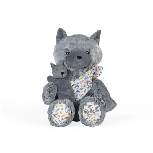 O bebé lobo aninhado no porta-bebés de musselina com estampa de folhagem, junto à mãe lobo de peluche.
