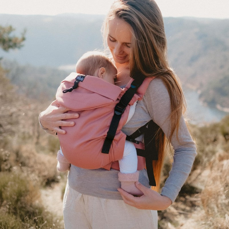 Mãe a carregar o bebé na frente com a Mochila Neobulle Néo+, mostrando a facilidade de uso.