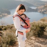 Mãe a utilizar a Mochila Neobulle Néo+ para transportar o seu bebé ao ar livre, destacando o ajuste confortável.