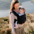 Mulher e bebé ao ar livre, com a Mochila Neobulle Ajustável ToddlerSize Ébène em destaque, mostrando a proximidade e conforto proporcionados pelo porta-bebés.