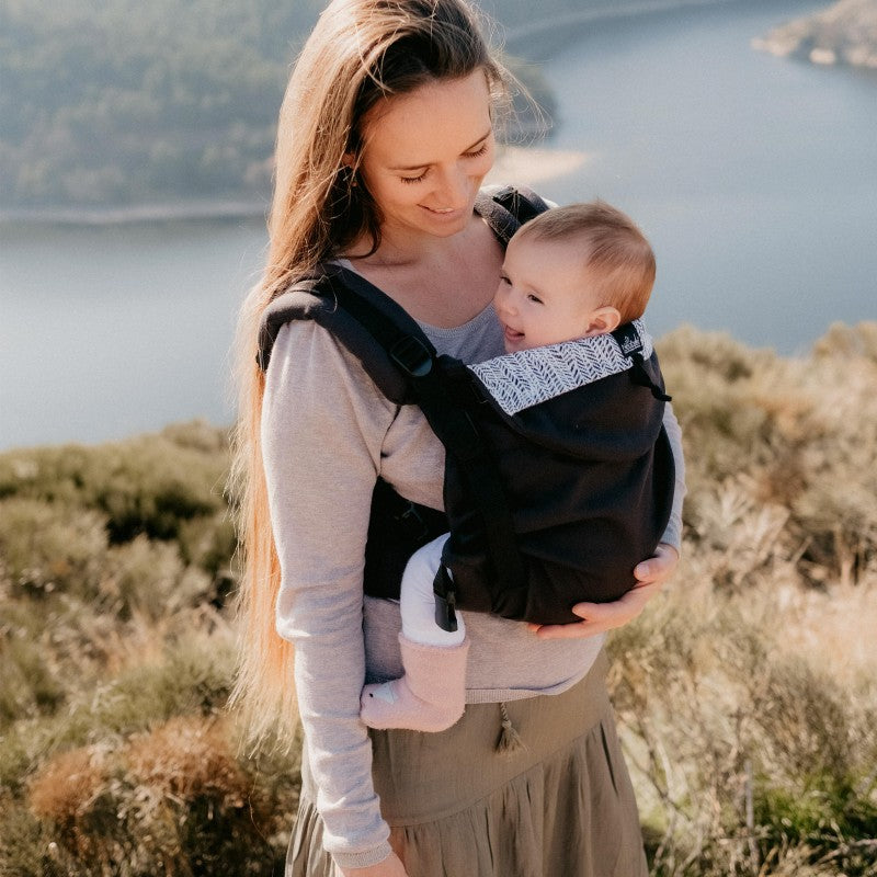 Mulher e bebé ao ar livre, com a Mochila Neobulle Ajustável ToddlerSize Ébène em destaque, mostrando a proximidade e conforto proporcionados pelo porta-bebés.