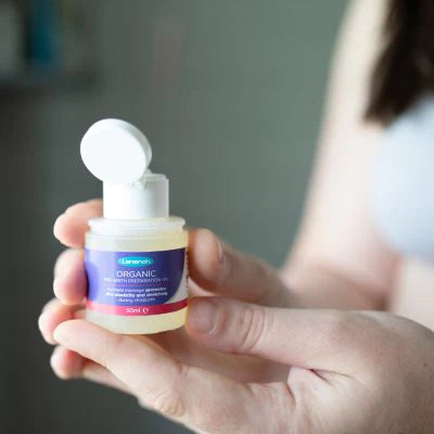 Óleo orgânico Lansinoh para preparação pré-parto sendo segurado por uma mão, mostrando o rótulo e a embalagem compacta de 50ml.