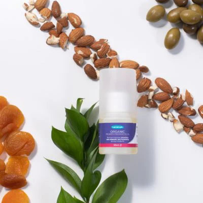 Frasco de óleo orgânico Lansinoh rodeado por ingredientes naturais como amêndoas, damascos secos e azeitonas, destacando sua composição orgânica.