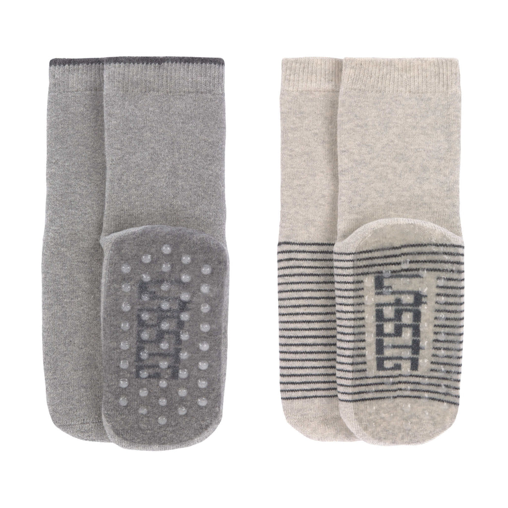 Conjunto de duas meias antiderrapantes Lassig, uma cinza e outra bege, com solas de silicone visíveis para segurança.