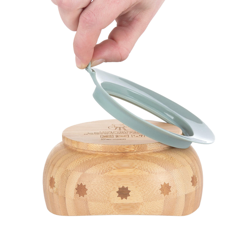 Mão a remover a ventosa de silicone da base da taça de bambu Lässig.