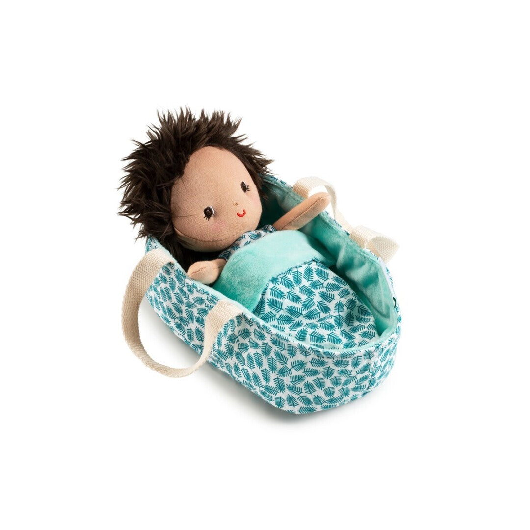 Boneca bebé Ari da Lilliputiens deitada na sua alcofa de tecido com padrão verde e branco.