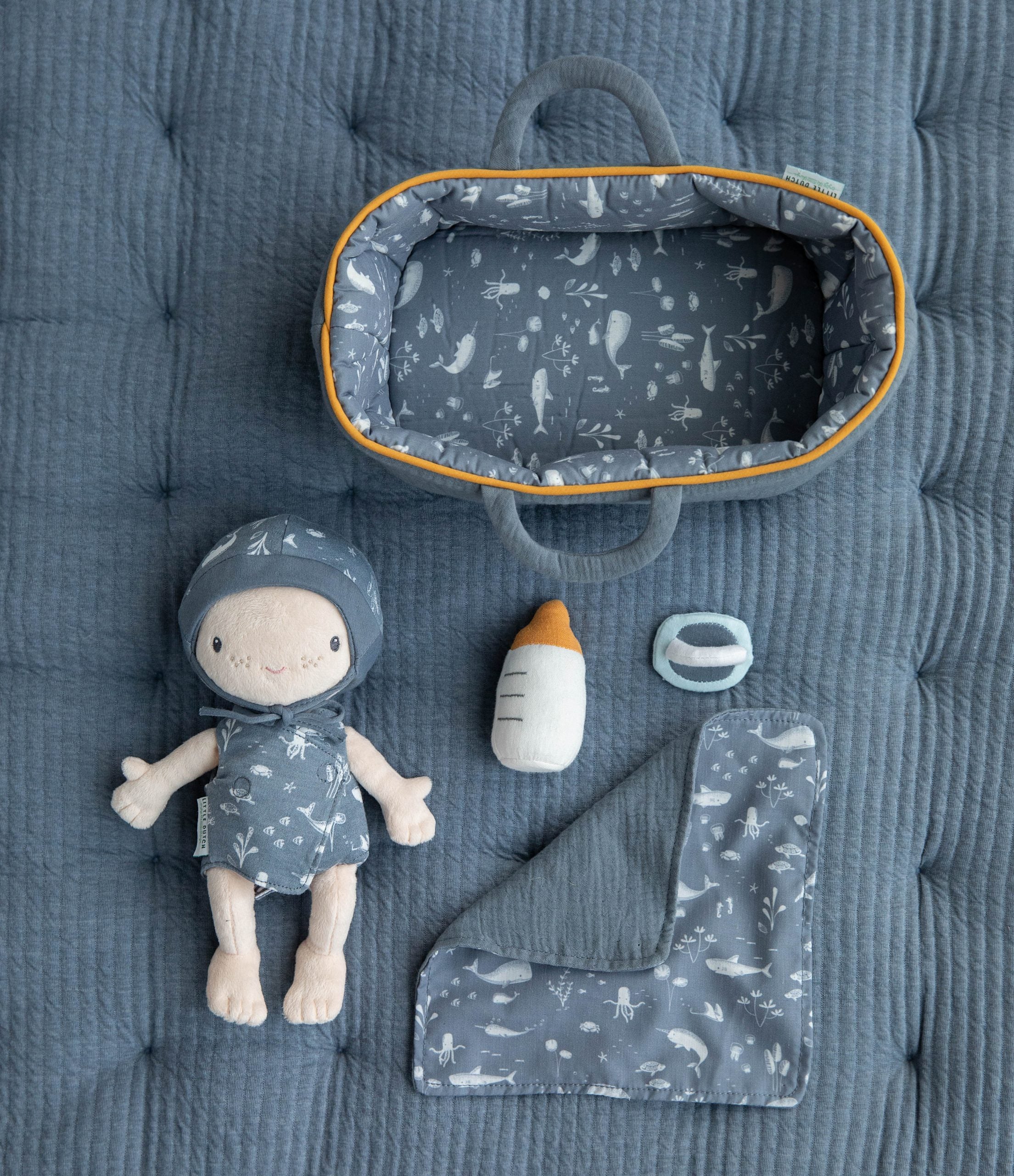 Alcofa de viagem do bebé Jim da Little Dutch, com padrão decorativo, mostrando o boneco aconchegado no seu interior.