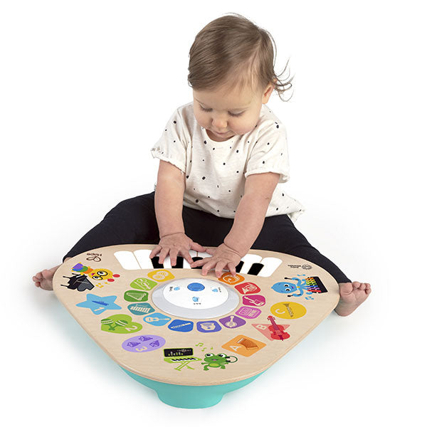 Bebé a brincar sentado no chão com a Hape Baby Einstein Mesa de Atividades Magic Touch, interagindo com o teclado.