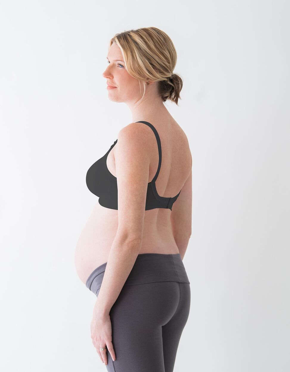 Modelo grávida usando o Sutiã Medela Comfy Preto XL, vista lateral, mostrando o ajuste durante a gravidez.