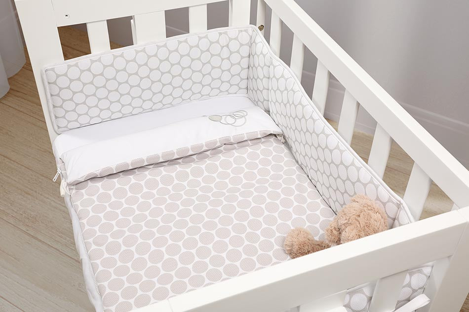 Kit protetor de berço Micuna com edredão saco na cor Branco, mostrando o protetor baixo e o saco de dormir preso ao colchão.