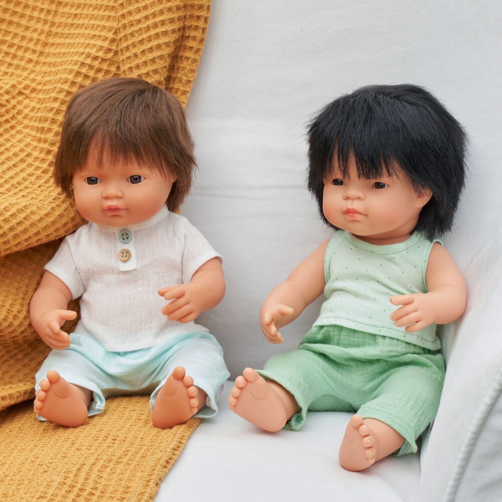 Boneco bebé Miniland caucasiano de 38cm, com cabelo loiro curto, vestido com cuecas brancas, em pose de pé. Foco no rosto realista.