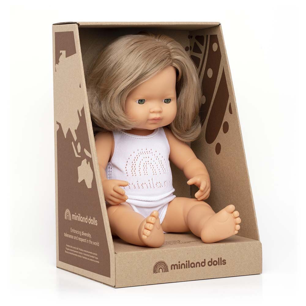 Boneca bebé Miniland caucasiana de cabelo louro sentada na sua embalagem de cartão, com roupa interior branca.