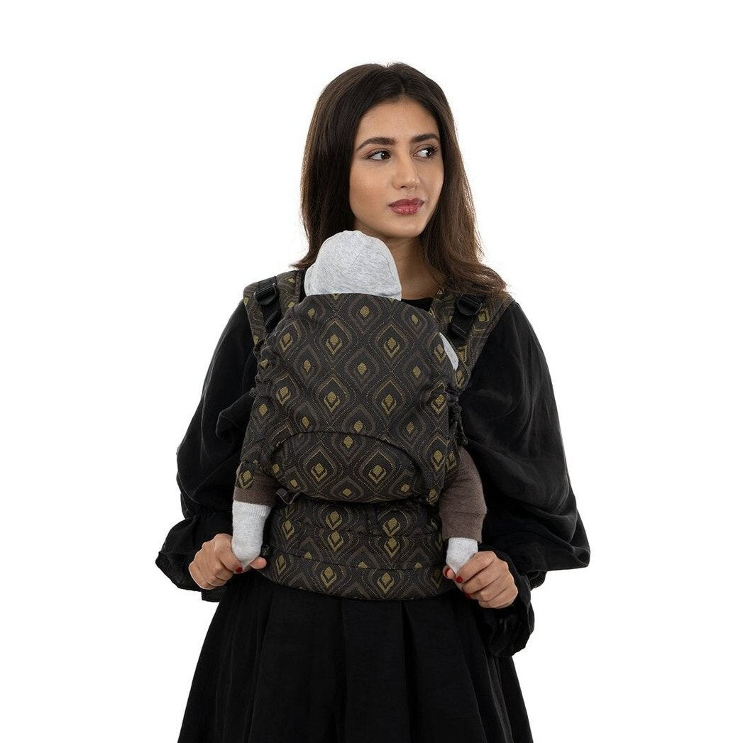 Mulher a usar a Mochila Fidella Fusion Evolutiva Peacock Gold com um bebé, de frente.