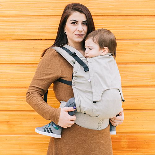 Mãe a utilizar a mochila ergonómica Neko Smart Moss com bebé ao colo.