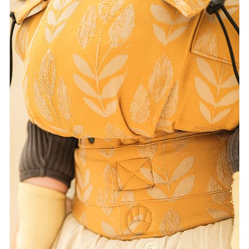 Vista lateral da mochila Neko ajustável em uso, destacando o posicionamento ergonómico do bebé (posição M) e o apoio total das costas.