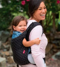Mulher a transportar um bebé nas costas usando a mochila ergonómica.