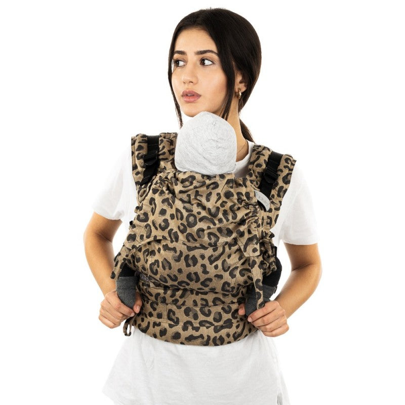 Mulher de frente a usar a mochila Fidella Fusion Evolutiva Leopard Gold, com o bebé visível no porta-bebé.