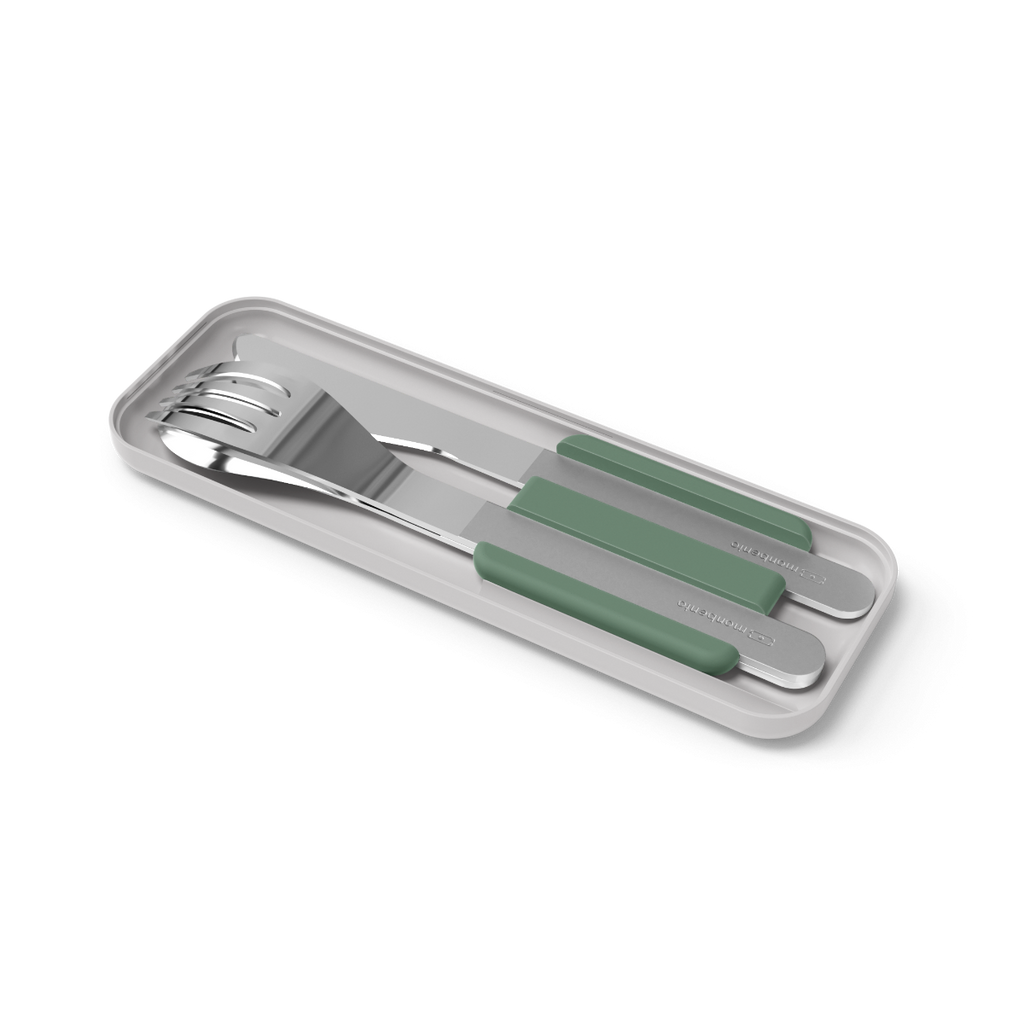 Conjunto completo de talheres Monbento (faca, garfo, colher) em aço inox com suportes verdes, apresentados no estojo de transporte cinza.