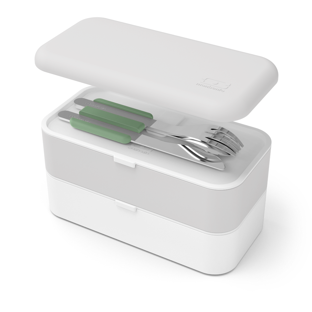 Talheres Monbento em aço inox com suporte verde guardados no estojo de transporte cinzento e branco, com tampa aberta.