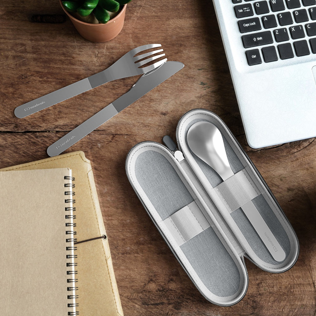 Conjunto completo de talheres Monbento Slim Nest: garfo, faca e colher de aço inoxidável, apresentados na sua bolsa de transporte cinzenta.