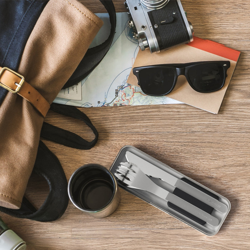 Conjunto completo de talheres Monbento em aço inoxidável (faca, garfo, colher) dentro do suporte flexível de silicone cinzento.