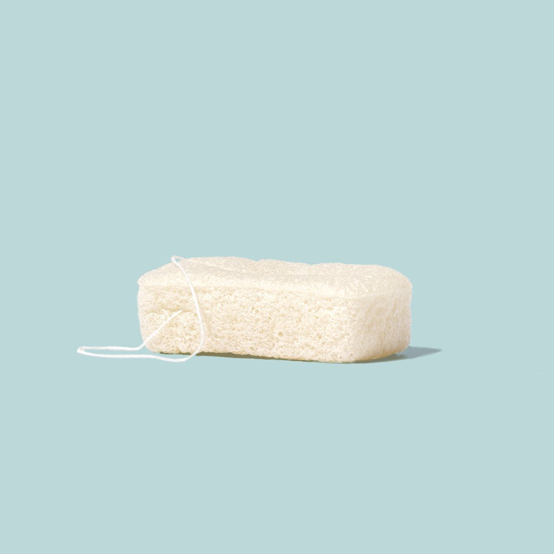 Esponja natural de Konjac da Naturbrush, ideal para limpeza e esfoliação suave do corpo, apresentada sobre um fundo azul claro.