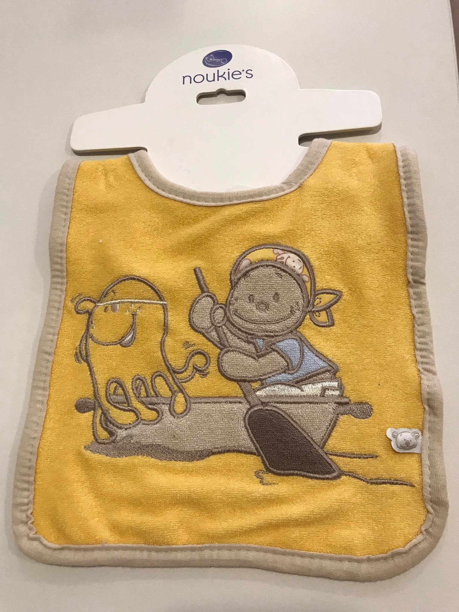 Vista frontal da babete Noukies aplicada num manequim de criança, destacando o design neutro e prático.