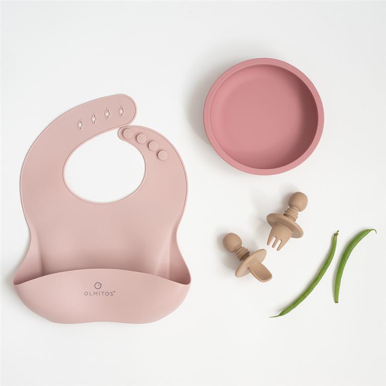 O conjunto completo de alimentação Olmitos (4 peças) em uso, com a tigela cheia de papa, o bebé a usar o babete e os talheres.
