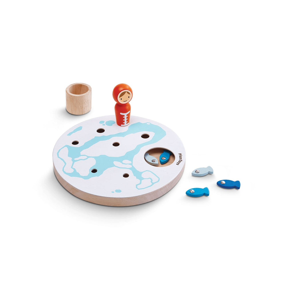 Imagem do jogo da pesca no gelo da PlanToys, mostrando todos os componentes: o tabuleiro circular com buracos, os peixinhos coloridos, o esquimó e o balde.