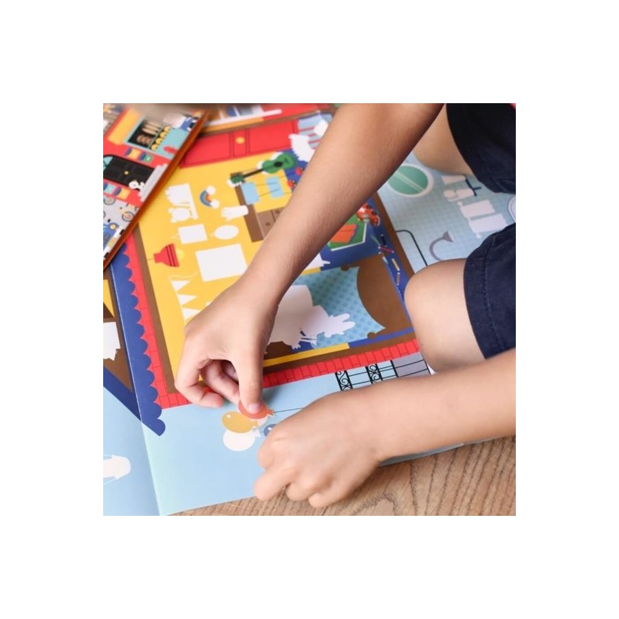 Mãos de uma criança a aplicar um autocolante circular no poster interativo Poppik, que está aberto sobre o chão, a montar a cena da casa.