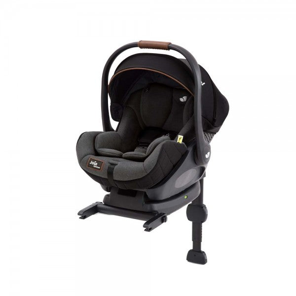 Vista frontal da cadeira auto i-Size com alça de transporte ajustada para trás, destacando o encosto de cabeça e o cinto de segurança.