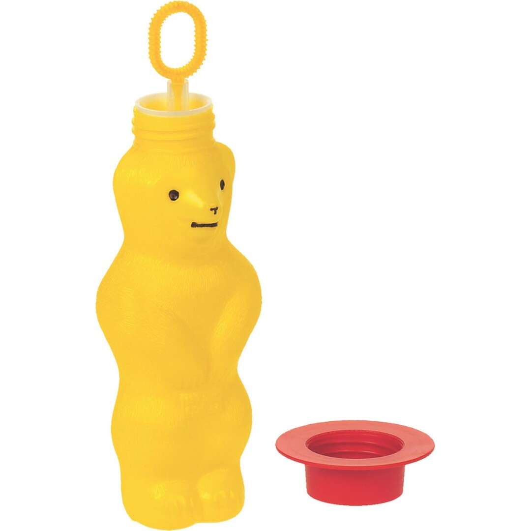 Uma menina soprando bolhas de sabão com o frasco em forma de urso vermelho da Pustefix. Bolhas grandes e brilhantes flutuam ao redor dela.
